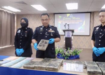 RAZLAN Ab Hamid (tengah) menunjukkan ketulan ganja mampat yang dirampas daripada seorang lelaki pada Khamis lalu dalam sidang akhbar di IPD Taiping hari ini. -  UTUSAN/WAT KAMAL ABAS