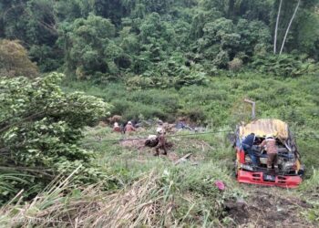 ANGGOTA bomba membantu mengeluarkan mangsa tersepit di dalam longkang selepas treler dipandunya terbabas ke dalam gaung di Gunung Paku, Klian Intan di Pengkalan Hulu, Perak. - IHSAN JBPM PERAK