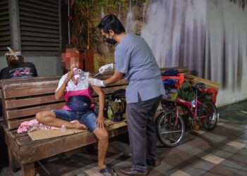 PETUGAS Jabatan Kesihatan menyuntik vaksin Covid-19 kepada seorang gelandangan wanita di Hentian Bas Majlis Bandaraya Kuala Terengganu di Kuala Terengganu, semalam. -  UTUSAN/PUQTRA HAIRRY ROSLI