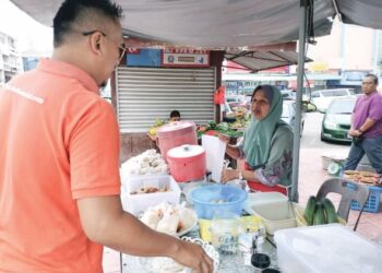 SALBIAH Atan melayan pelanggan di gerai jualannya di kaki lima sebuah bank di Jalan Datuk Haji Hassan, Kluang, Johor.