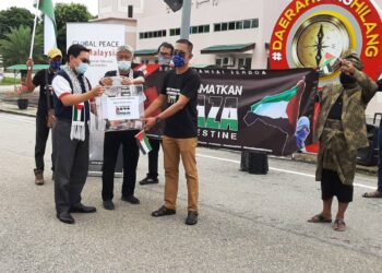 HASAN Rahman (tengah) memasukkan sumbangan ke Tabung Selamatkan Palestin peringkat DUN Sungai Rambai sambil diperhatikan Ahmad Fahmi Mohd. Samsudin (kiri) di Japerun Sungai Rambai, Jasin, Melaka. - UTUSAN/AMRAN MULUP