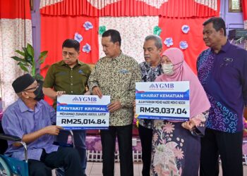 ABDUL Muie Ngah (tiga, kiri) menyampaikan manfaat penyakit kritikal sambil diperhatikan Wan Munadi Wan Mamat (dua, kiri) pada majlis penyampaian manfaat penyakit kritikal dan khairat kematian di Kuala Terengganu, hari ini. - UTUSAN/PUQTRA HAIRRY ROSLI
