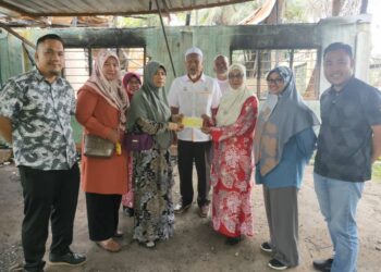 ZARIAH Harun (tiga kanan) menyampaikan sumbangan Tabung Kebajikan Kecemasan Peneroka (TKKP) bernilai RM40,000 kepada Siti Hajar Abd. Latif (tiga kiri) di Felda Jengka 2 di Maran, Pahang. - FOTO/SALEHUDIN MAT RASAD