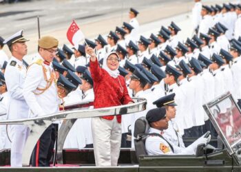 HALIMAH mengibarkan bendera semasa sambutan Hari Kebangsaan ke-54 di Singapura, 2019. – AFP