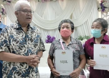 HAMZAH Zainudin (kiri) menyerahkan dokumen pengenalan diri kepada dua bersaudara di JPN Larut Matang dan Selama di Taiping, Perak.- UTUSAN/WAT KAMAL ABAS