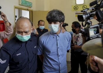 TOH Han Boon diiringi polis ketika dihadapkan ke mahkamah bagi menghadapi tuduhan mengedar filem dan mempamerkan poster filem tanpa lesen sah di Mahkamah Majistret Petaling Jaya, Selangor. - UTUSAN/SHIDDIEQIIN ZON