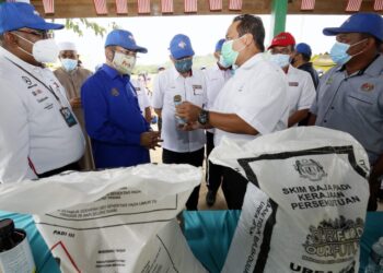 NIK Muhammad Zawawi Salleh (dua dari kiri) mendengar taklimat mengenai baja urea biru yang digunakan oleh petani di Kampung Nam Dam, Pendang, Kedah, hari ini. - UTUSAN/MOHD. RIFAAT ABD. HAMID