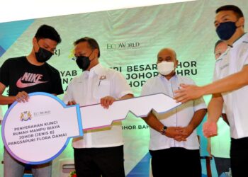 HASNI Mohammad (tengah) menyerahkan replika kunci kepada salah seorang penerima rumah sempena Majlis Penyerahan Kunci Rumah Kos Rendah Taman Setia Indah di Pusat Komuniti Taman Ekoflora di Johor. -UTUSAN/RAJA JAAFAR ALI