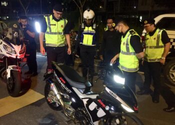 ZULKARNAIN Yasin (kiri) memeriksa sebuah motosikal yang diubah suai pada Operasi Khas Ambang Tahun Baharu 2023 di Gong Badak, Kuala Nerus, Terengganu, malam tadi. - UTUSAN/TENGKU DANISH BAHRI TENGKU YUSOFF
