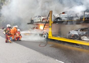 PASUKAN bomba bertungkus-lumus memadam kebakaran melibatkan lori bersendi yang membawa kereta baharu dalam kejadian di Kilometer 227.2 Lebuh Raya Utara Selatan (arah Utara), dekat Pedas, Rembau, Negeri Sembilan, petang inii. - IHSAN BOMBA