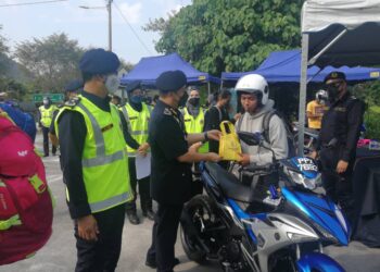 AEDY Fadly Ramli menyerahkan sumbangan kepada penunggang motosikal ketika melancarkan Op Tahun Baharu Cina di Kilometer 1, Jalan Simpang Pulai-Cameron Highlands dekat Ipoh hari ini.