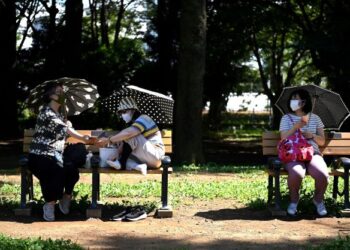 PENGUNJUNG duduk di bangku semasa musim panas di taman Yoyogi,Tokyo.-AFP
