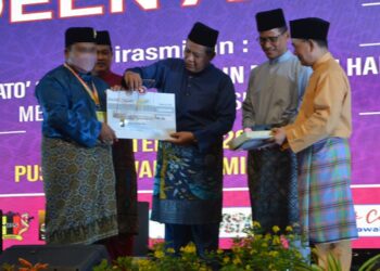 AMINUDDIN Harun (tengah) bersama Sutekno Ahmad Belon (kanan) menyampaikan hadiah kepada pemenang dalam Pogram i-Deen di Seremban semalam. - UTUSAN/ZAKKINA WATI AHMAD TARMIZI
