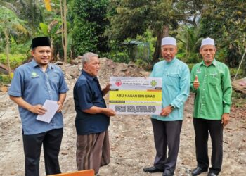 IDRIS Ahmad (dua dari kanan) menyampaikan cek bantuan baik pulih rumah kepada seorang penduduk, Abu Hassan Saad di Changkat Ibol di Bukit Gantang hari ini. - UTUSAN/WAT KAMAL ABAS