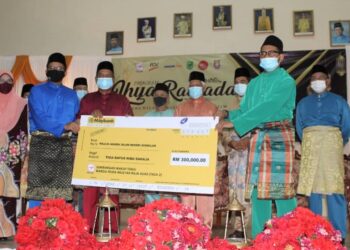 KARIP Mohd. Salleh (tiga dari kiri) menyerahkan replika cek Sumbangan Wakaf Tunai Warga Felda Wilayah Raja Alias (Fasa 2) kepada Ahmad Husaini sambil diperhatikan oleh Idris Jusoh (empat dari kanan) pada Program Ihya Ramadan Felda Wilayah Raja Alias di Dewan Semai Bakti Felda Jelai 3, Gemas, Tampin hari ini.- UTUSAN/NOR AINNA HAMZAH.