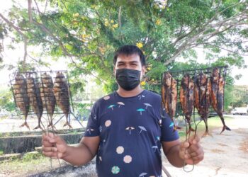 MUHAMAD Shafian Amran menunjukkan ikan cencaru sumbat yang dijual RM1.50 seekor di gerainya di Kawasan Perindustrian Pengkalan Chepa, Kota Bharu semalam. - UTUSAN/YATIMIN ABDULLAH