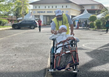 MOHD. Jelani Mat Akhir dibantu petugas setelah selesai mengundi di Kolej Tingkatan Enam Sultan Sallehuddin di Pokok Sena. -UTUSAN/JAMLIAH ABDULLAH