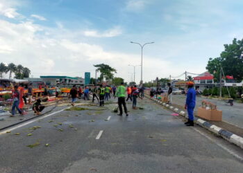 ANGGOTA APM Kubang Pasu bersama petugas agensi lain dan orang ramai membersihkan jalan raya yang terjejas akibat ribut di Jalan Utama Jitra - Changlun di Kubang Pasu.