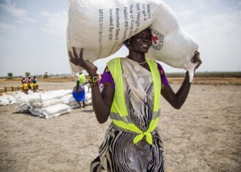 SUKARELAWAN tempatan menjunjung seguni benih di pekan Thonyor, Sudan Selatan.-AFP