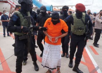 ANGGOTA polis mengawal ketat pemimpin kanan JI yang didakwa dalang pengeboman di Bali 2002, semasa ketibaan di Lapangan Terbang Antarabangsa Soekarno-Hatta di Tangerang, tahun lalu.-AFP