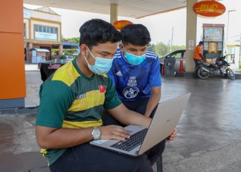 Pelajar tingkatan 5, Muhammad Arissyafiq Mohamad Arishan (kiri) dan Luqman Hakim Mad Isa terpaksa menumpang kemudahan internet di sebuah stesen minyak di Kampung Barokhas, Kuala Nerang, semalam untuk mengikuti kelas dalam talian.