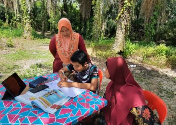 NOR Arzila Abd. Rashid  (kiri) dan Sariah Ahmad (kanan) memerhatikan Muhammad Farith Iskandar Farizul menyiapkan kerja-kerja sekolah di bawah pokok kelapa sawit bagi mendapatkan liputan internet yang lancar di Kampung Permatang Kerat Telunjuk, Bandar Baharu, Kulim, Kedah. – UTUSAN/AZAHAR HASHIM.