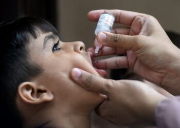 PETUGAS kesihatan memberikan titisan vaksin semasa kempen vaksinasi polio di Karachi, Pakistan.-AFP