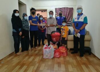OSMAN Sapian (tengah) menyampaikan sumbangan kepada Muhammad Aqib Mohd. Nor Hafiz ketika melawat keluarga itu di PPR Permai, Kempas di Johor. -UTUSAN/MOHAMAD FAIZAL HASHIM
