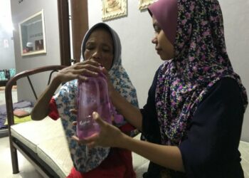 NOR Syuhadah Aziz (kanan) memberi minuman kepada Noraini Ismail di rumah mereka di Kampung Limau Kasturi 2, Gua Musang, Kelantan.
