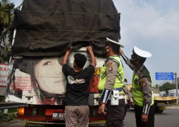 Polis memeriksa kenderaan yang keluar dari Jakarta. - AFP