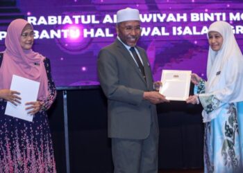 IDRIS Ahmad menyampaikan Anugerah Perkhidmatan Cemerlang kepada pembantu Hal Ehwal Islam, Rabiatul Adawiyah Mohamed (kanan) pada Majlis Anugerah Perkhidmatan Cemerlang (APC) Tahun 2021 Jabatan Perdana Menteri (Hal Ehwal Agama) di Kompleks Islam Putrajaya di sini, hari ini. - UTUSAN/FAISOL MUSTAFA