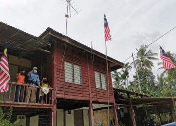 SALIM Abdul Hamid dan dua cucunya melihat Jalur Gemilang yang mereka pasang di Kampung Tebing Rebak dekat Bagan Datuk semalam. – UTUSAN/AIN SAFRE BIDIN