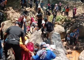 ORANG ramai membantu pengunjung yang cedera selepas jambatan runtuh dipercayai 'angkara' budak nakal mengalihkan tanda amaran pada jambatan gantung yang masih diselenggara di Lata Keding, Jeli, Kelantan, semalam. – MEDIA SOSIAL