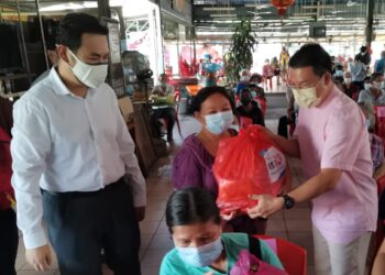 NGA Kor Ming (kanan) menyampaikan sumbangan bakul makanan kepada penduduk di Mambang Diawan, Kampar, Perak, hari ini.