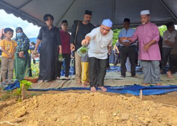 SAARANI Mohamad menyiram air di kubur ibunya pada pengebumian di Tanah Perkuburan Islam Kampung Raban di Lenggong hari ini. - UTUSAN/SAYED HESHAM IDRIS