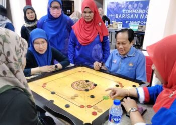 AHMAD Maslan (kanan) menyaksikan pertandingan karom pada Sukan Wanita UMNO Bahagian Pontian di Pontian, Johor, hari ini.