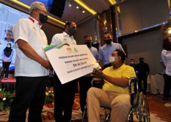 M. Saravanan (dua kiri) menyampaikan replika cek bernilai RM48,356.49 kepada Radin Sutrisno Radin Sudar Sono yang hilang upaya kekal akibat kemalangan jalan raya sambil diperhatikan Noh Omar sempena Majlis Pelancaran Kempen Mencarum Perkeso Usahawan Tekun di,  Johor Bahru hari ini. UTUSAN/RAJA JAAFAR ALI