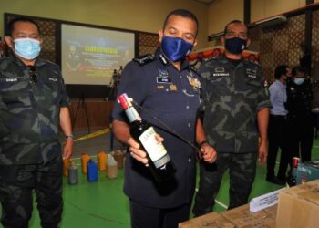 AYOB Khan Mydin Pitchay (tengah) melihat arak tiruan yang berjaya dirampas dalam Op Kontraban di Taman Ungku Tun Aminah, Skudai pada sidang akhbar di IPK, Johor Bahru di Johor. -UTUSAN/RAJA JAAFAR ALI