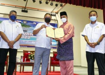 HASNI Mohammad (dua kiri) menyampaikan sijil hak milik tanah kepada peneroka pada Majlis Penyerahan Hak Milik Peneroka Felda Tenggaroh 1 dan Tenggaroh 7 di Dewan Jubli Intan Sultan Ibrahim, di Mersing, Johor.