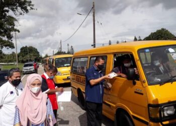 CHE Zakaria Mohd. Salleh (kanan) menyerahkan sumbangan secara pandu lalu kepada pengusaha dan pemandu van sekolah di Taman Bukit Dahlia, Pasir Gudang, di Johor. -UTUSAN/KHAIRUL MOHD ALI
