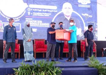 RONALD Kiandee (tiga dari kiri) menyampaikan bantuan kelengkapan kepada nelayan ketika hadir Jelajah Dialog Industri Agromakanan Bersama Komuniti Agromakanan Negeri Johor di Kompleks LKIM Endau, Mersing.