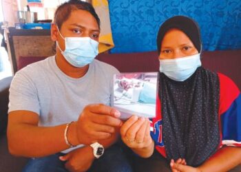 HANYA sekeping gambar Nur Qaira Qalisha yang menjadi pengubat rindu Mohd. Suhaimi Jasmin (kiri) dan Asfanizan Othman ekoran bayi mereka yang dirawat di HSA ketika ditemui di Taman Sinar Sedili, Tanjung Sedili di Kota Tinggi, Johor. -UTUSAN/MASTURAH SURADI