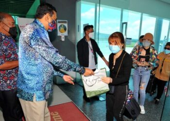 R. SANTHARA Kumar (dua dari kiri) bersama Suhairi Hashim (kiri) menyampaikan cenderamata kepada pelancong dari Vietnam yang tiba melalui penerbangan antarabangsa pertama yang mendarat di Lapangan Terbang Antarabangsa Senai, Kulai, Johor. - FOTO/RAJA JAAFAR ALI