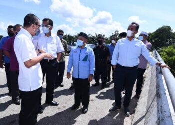 TUAN Ibrahim Tuan Man (tengah) meninjau sistem perparitan sempena lawatan ke tapak projek Rancangan Tebatan Banjir di sekitar Kampung Parit Basri, Sri Medan, Batu Pahat. UTUSAN/NUR ALINA HASSAN