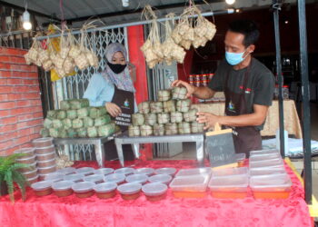 AZURA Ahmad (kiri) dan Mohd. Nazri Mohd. Rozali menyusun jualan makanan seperti ketupat, burasak dan lepat lui di kedai mereka di Taman Bakek, Jalan Bakek, Pontian, Johor. - UTUSAN/MUHAMMAD ZIKRI