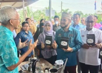 NIK MUHAMMAD Zawawi (dua dari kanan) mendengar penerangan tentang Kopi Rimau daripada Pengusaha Kopi Batu Pahat, Esham Salam (kiri) pada sambutan Hari Kelapa dan Kopi 2022 di Pusat Pertanian Parit Botak, Batu Pahat, Johor.