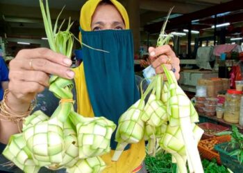 SARIMAH Alias menunjukkan kelongsong ketupat yang dihasilkannya bagi memenuhi permintaan pelanggan sempena musim perayaan di Pasar Besar Awam Bandar Segamat, Johor. - UTUSAN/FARAHWAHIDA AHMAD