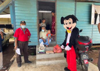 KEHADIRAN maskot Mickey Mouse menceriakan program penyampaian sumbangan daripada I Kasih di Kampung Parit Dato Onn, Pontian, Johor. - UTUSAN/MUHAMMAD ZIKRI