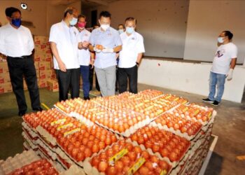 MOHD. Hairi Mad Shah (dua dari kanan) melihat susunan telur sebelum diagihkan kepada orang ramai sempena Program Bank Makanan di Dewanraya Taman Perbadanan Islam, Kebun Teh di Johor Bahru, Johor. -UTUSAN/RAJA JAAFAR ALI