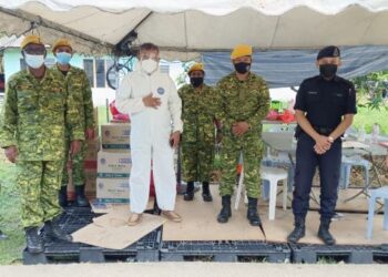 CHE Zakaria Mohd. Salleh (tengah) yang memakai pakaian perlindungan diri ketika menyerahkan sumbangan kepada petugas barisan hadapan di kawasan PKPD di Kampung Orang Asli Kuala Masai, Pasir Gudang, di Johor.